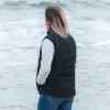 A picture of a woman with her back to the camera wearing a black puffer style vest.