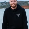 A smiling man wearing a black sweatshirt with The Winey Cow logo in white on his chest.