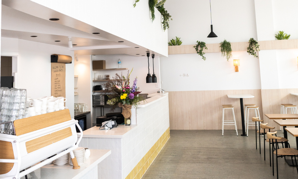 Bright and modern café interior at The Winey Cow Main Beach with coffee bar, fresh flowers, and relaxed seating